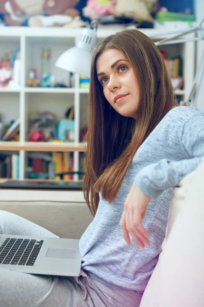 Flickan sitter i soffan med datorn. — Stockfoto