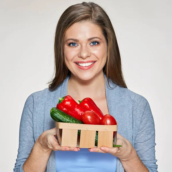 Leende kvinna anläggning korg med paprika, tomat, gurka. — Stockfoto