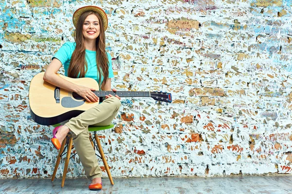 Usměvavá dívka s kytarou, sedí na židli. — Stock fotografie