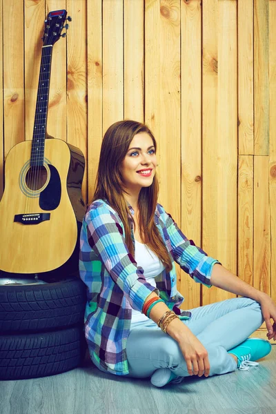 Mujer sentada en el suelo con guitarra y neumáticos — Foto de Stock