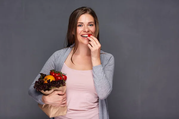 Vrouw met papieren zak met groenten eten van tomaat. — Stockfoto