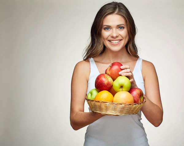 Mujer sonriente sosteniendo cesta de paja con frutas . — Foto de Stock