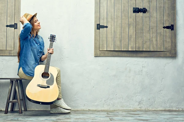 Frau sitzt mit Gitarre auf Straßenbank — Stockfoto