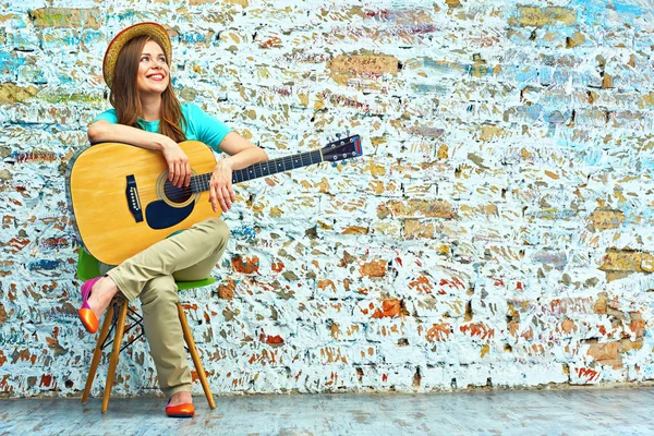 Usměvavá mladá žena sedící s kytarou — Stock fotografie