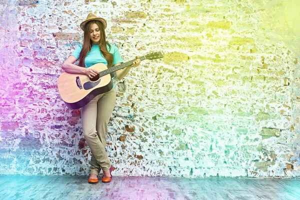 Kvinna som spelar gitarr mot tegelvägg — Stockfoto