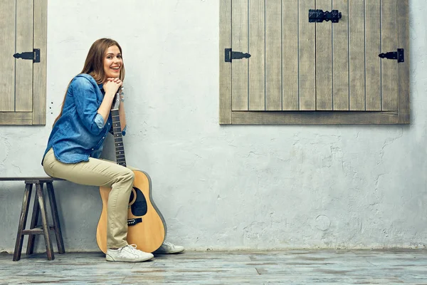 Kvinnan som sitter på gatan bänk med gitarr — Stockfoto