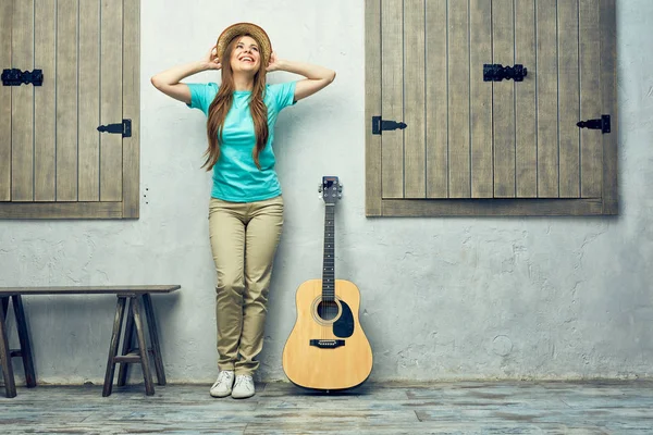 Woman with guitar leaning on light wall — Stock Photo, Image