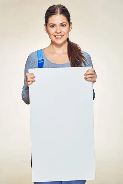 Mujer sonriente en la bata del constructor sosteniendo gran tablero de publicidad —  Fotos de Stock