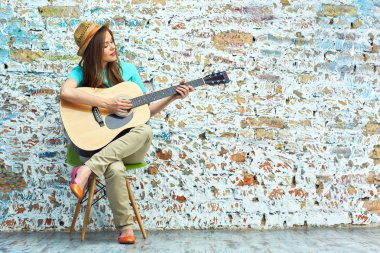 Gülümseyen kadın oturuyor ve gitar çalmak