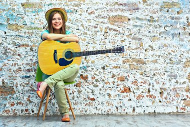 Gülümseyen kadın gitar ile oturuyordu