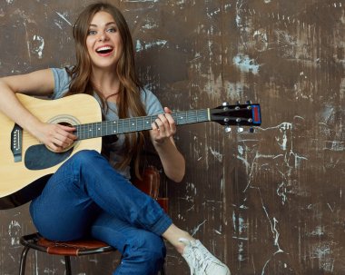 Gülümseyen kadın oturuyor ve gitar çalmak