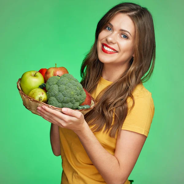 Meyve ve sebze ile hasır sepet tutan genç gülümseyen kadın