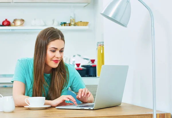 Jeune femme travaillant dans la cuisine avec ordinateur portable . — Photo