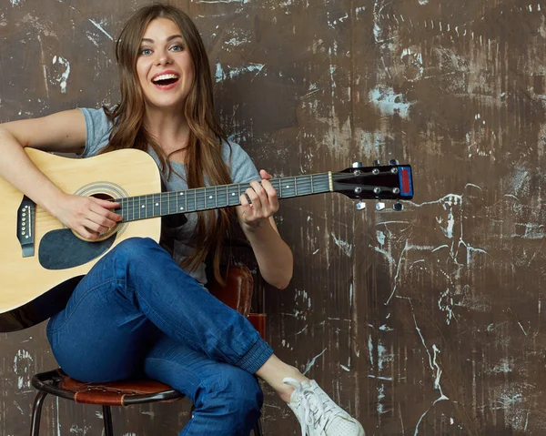 Mulher sorridente sentada e tocando guitarra — Fotografia de Stock