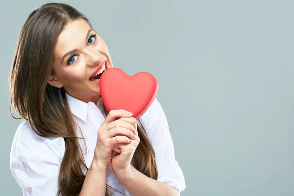 Beautiful woman biting red heart — Stock Photo, Image