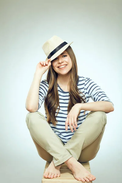 Smiling girl sitting on chair wearing hat. — Stock Photo, Image