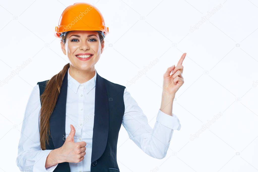 Woman builder in helmet points finger at copy space on white ba