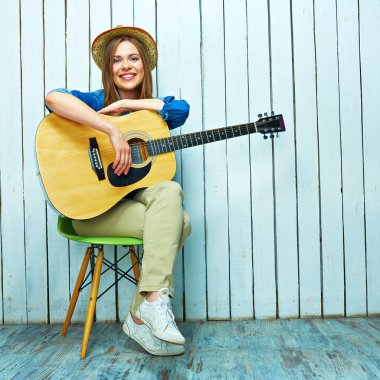 Gülümseyen genç kadın gitar ile oturuyordu