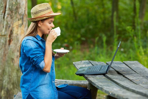 Žena pití kávy a pomocí přenosného počítače — Stock fotografie