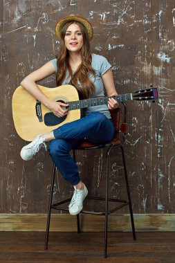 Gülümseyen kadın oturuyor ve gitar çalmak