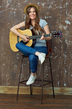Gülümseyen kadın oturuyor ve gitar çalmak