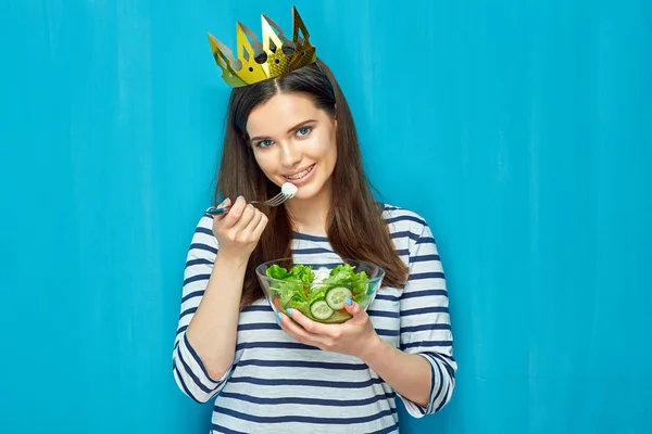 Leende flicka bära krona äta sallad. — Stockfoto