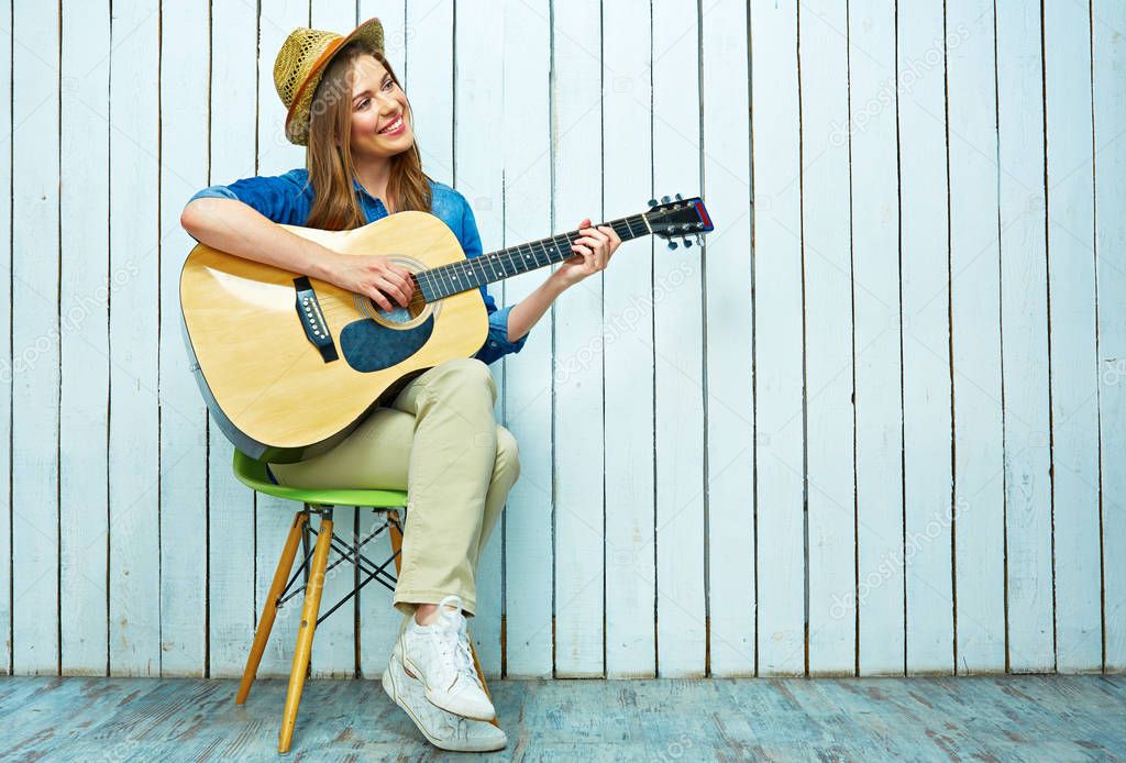 Smiling young woman plying guitar