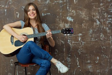 Gülümseyen kadın oturuyor ve gitar çalmak