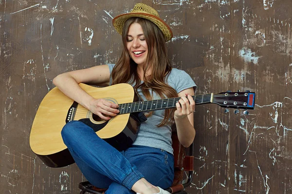 Smiling woman sitting and playing guitar — Stock Photo, Image