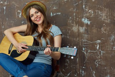 Gülümseyen kadın oturuyor ve gitar çalmak