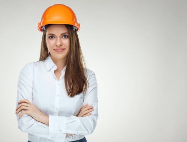 beyaz gömlek ve koruyucu kask ayakta çapraz silah ile gülümseyen kendine güvenen kadın builder mimar 