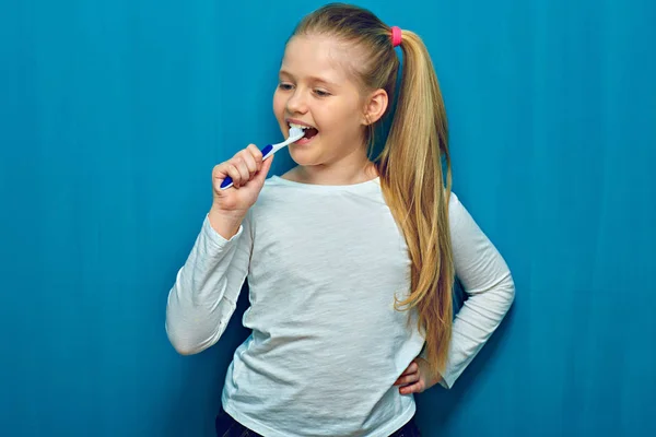 Liten flicka med långa blonda hår rengöring tänder med toothy bru — Stockfoto