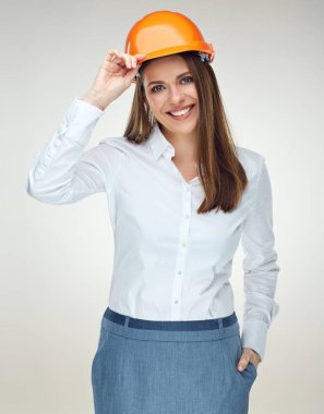 Oluşturucu kaskı takıyor ve kameraya bakarak gülümseyen kadın mühendis 