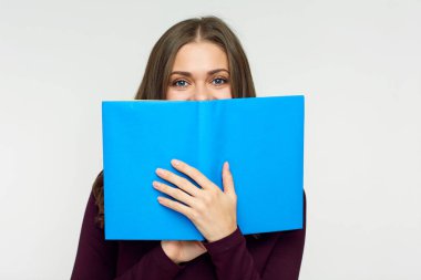 Öğrenci kız sakladığını yüz mavi kitap behind. 