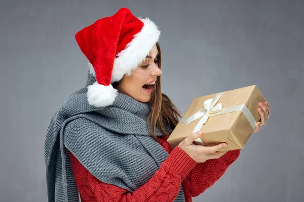 Happy Santa girl holding Christmas gift, wearing red hat. — Stock Photo, Image