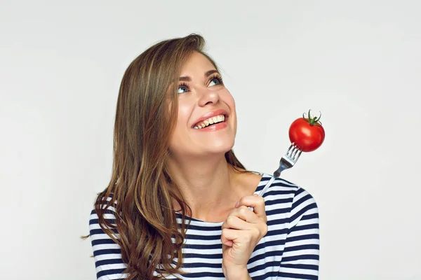 Leende kvinna anläggning tomat på gaffel tittar upp. — Stockfoto