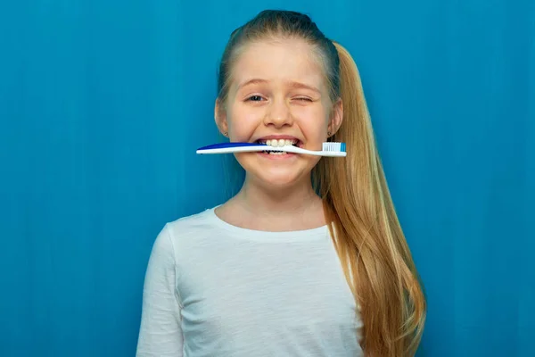 Liten flicka håller toothy borste med tänder. — Stockfoto