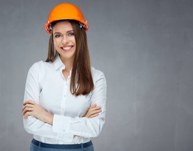 beyaz gömlek ve koruyucu kask ayakta çapraz silah ile gülümseyen kendine güvenen kadın builder mimar 