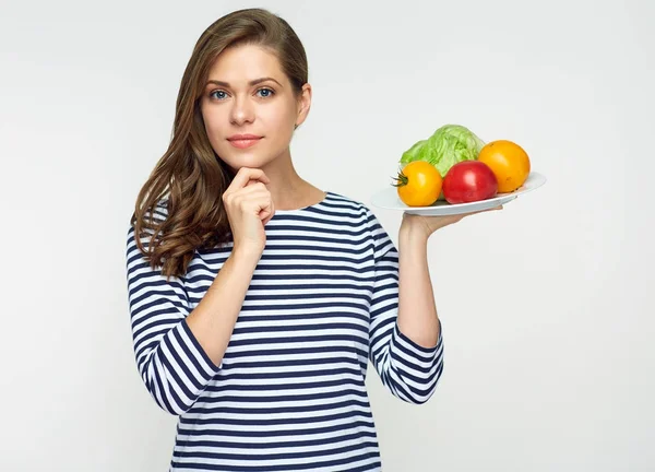 Leende ung kvinna håller plattan med grönsaker. — Stockfoto