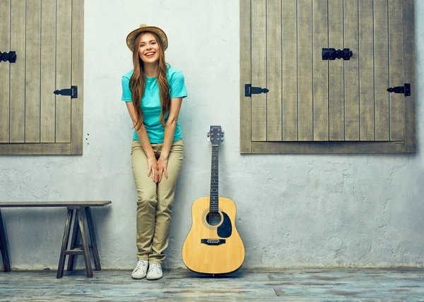 Vrouw met gitaar leunend op bakstenen muur — Stockfoto