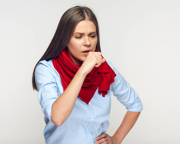 sick woman with red scarf on neck coughing on gray wall background