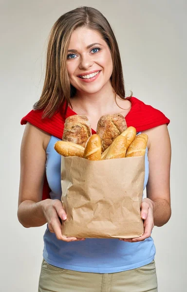 Smiling young woman holding paper bag with bread. — Stock Photo, Image