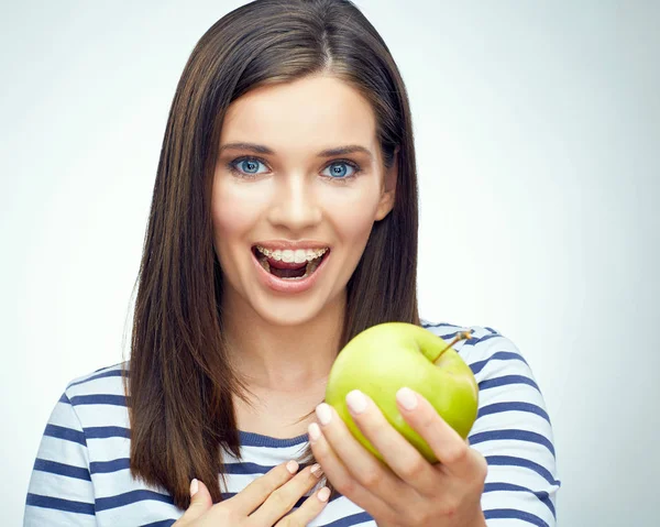 Дівчина посміхається зубами і зубними дужками тримає зелене яблуко — стокове фото