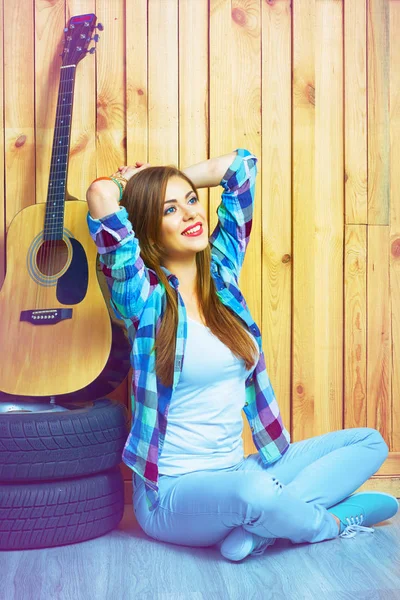 Kobieta siedzi na podłodze z gitara i opony — Zdjęcie stockowe
