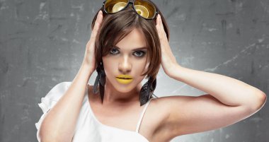 güzel genç modeli Güneş gözlüğü ve çıplak omuz ile beyaz gömlek giymiş dudaklarında sarı ruj ile