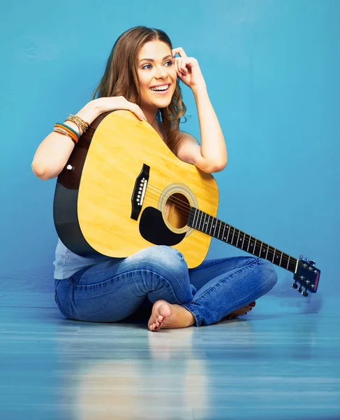 时尚音乐与年轻模特握着原声吉他 坐在蓝色的地板上 — 图库照片