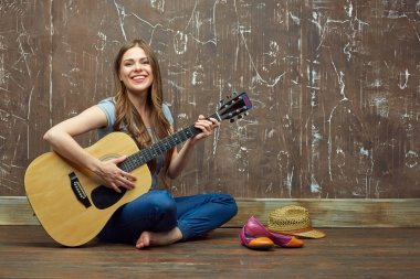 Güzel genç kadın yerde otururken akustik gitar çalmak
