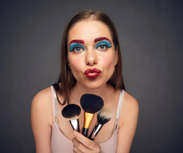 makeup master woman holding brushes on grey background, close-up