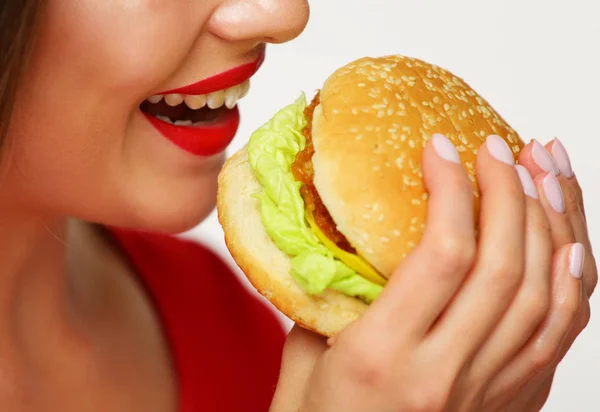 红色嘴唇的愉快的妇女拿着汉堡在黄色背景 — 图库照片