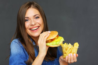 hamburger ve patates kızartması tutan kot gömlek gülümseyen kadın 